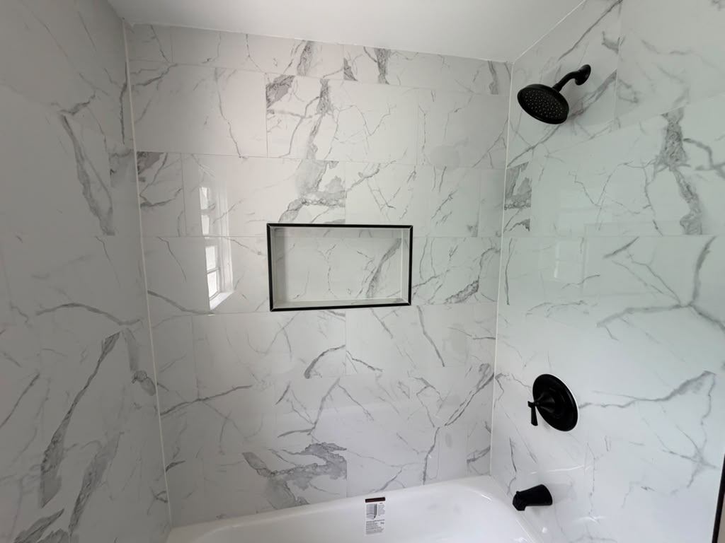 Marble-look tile shower surround with black shower fixtures