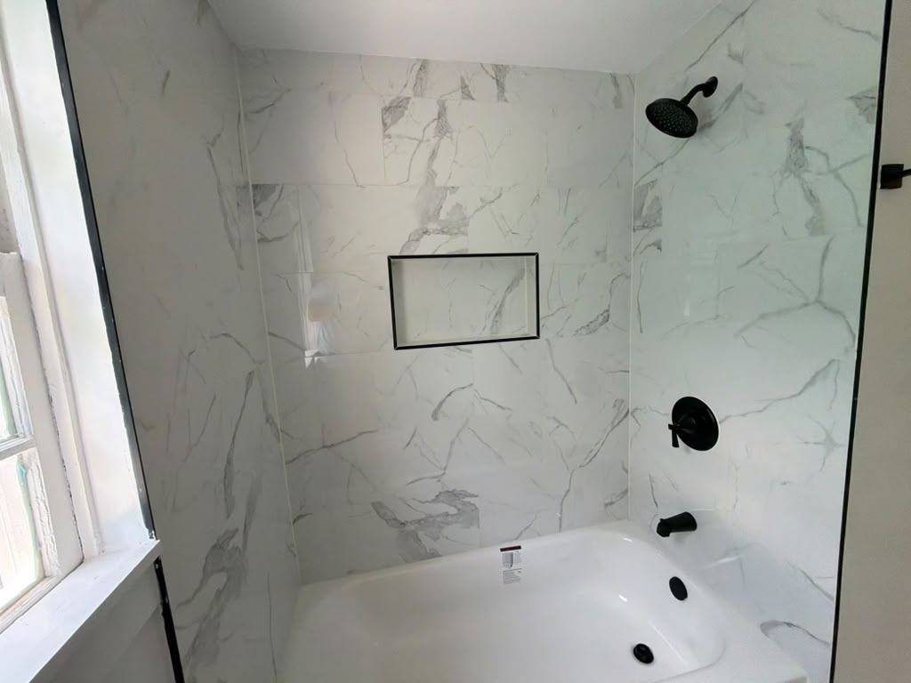 Renovated bathroom with full-height tile tub surround and matte black fixtures