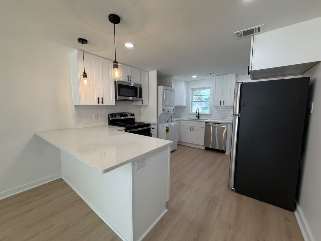 Full view of a renovated rental kitchen with white shaker cabinets