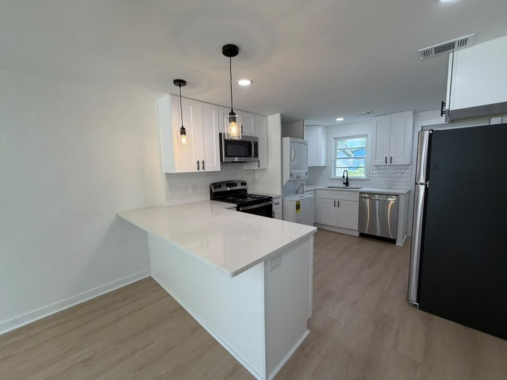 Kitchen peninsula with quartz countertop and stainless appliances