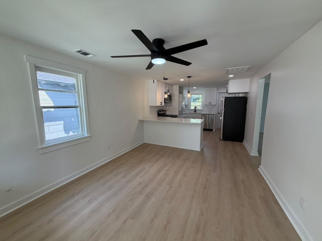 Open living area with new luxury vinyl plank flooring looking toward the renovated kitchen