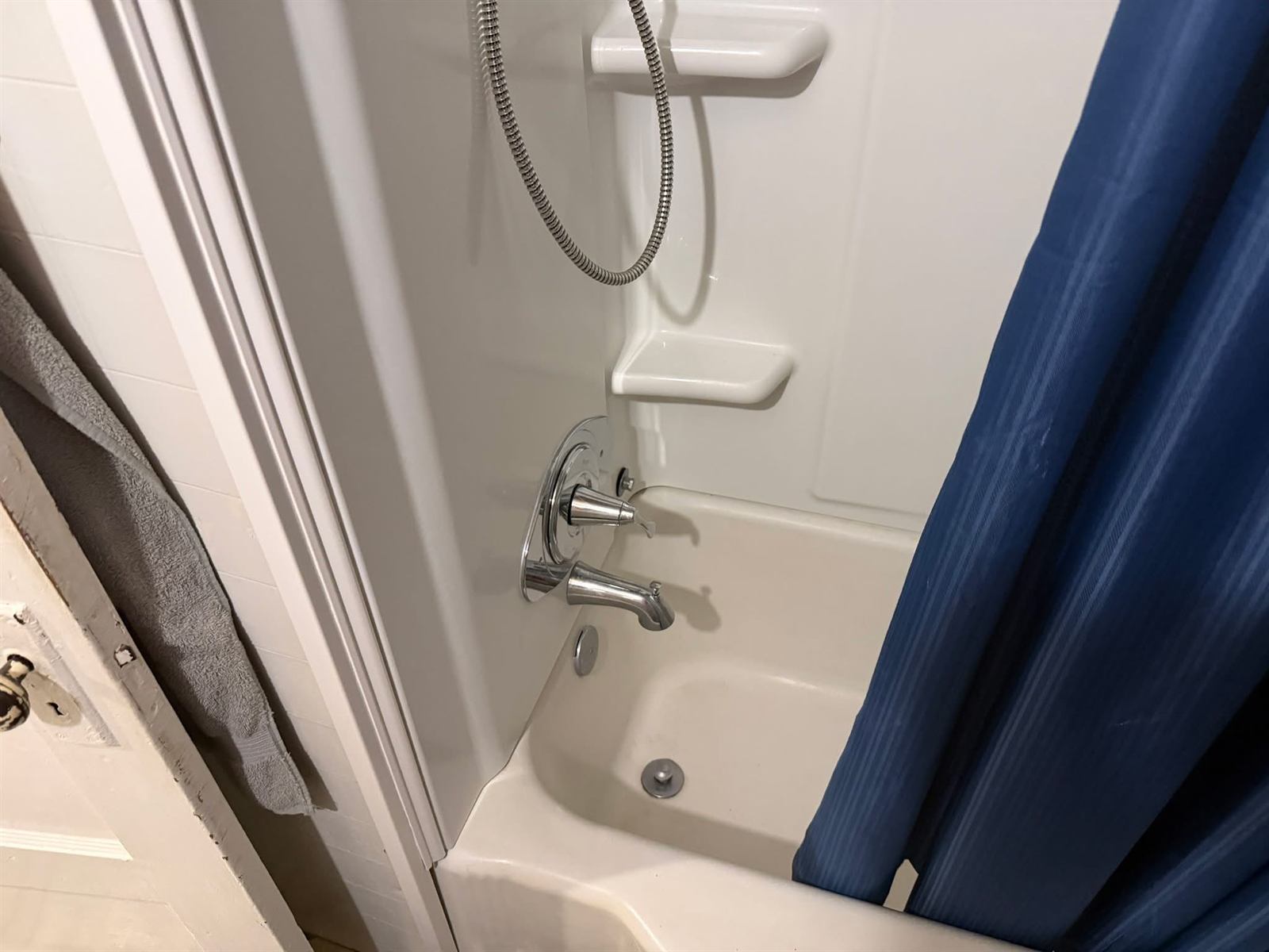 Bathroom before renovation with dated fiberglass tub surround and chrome fixtures