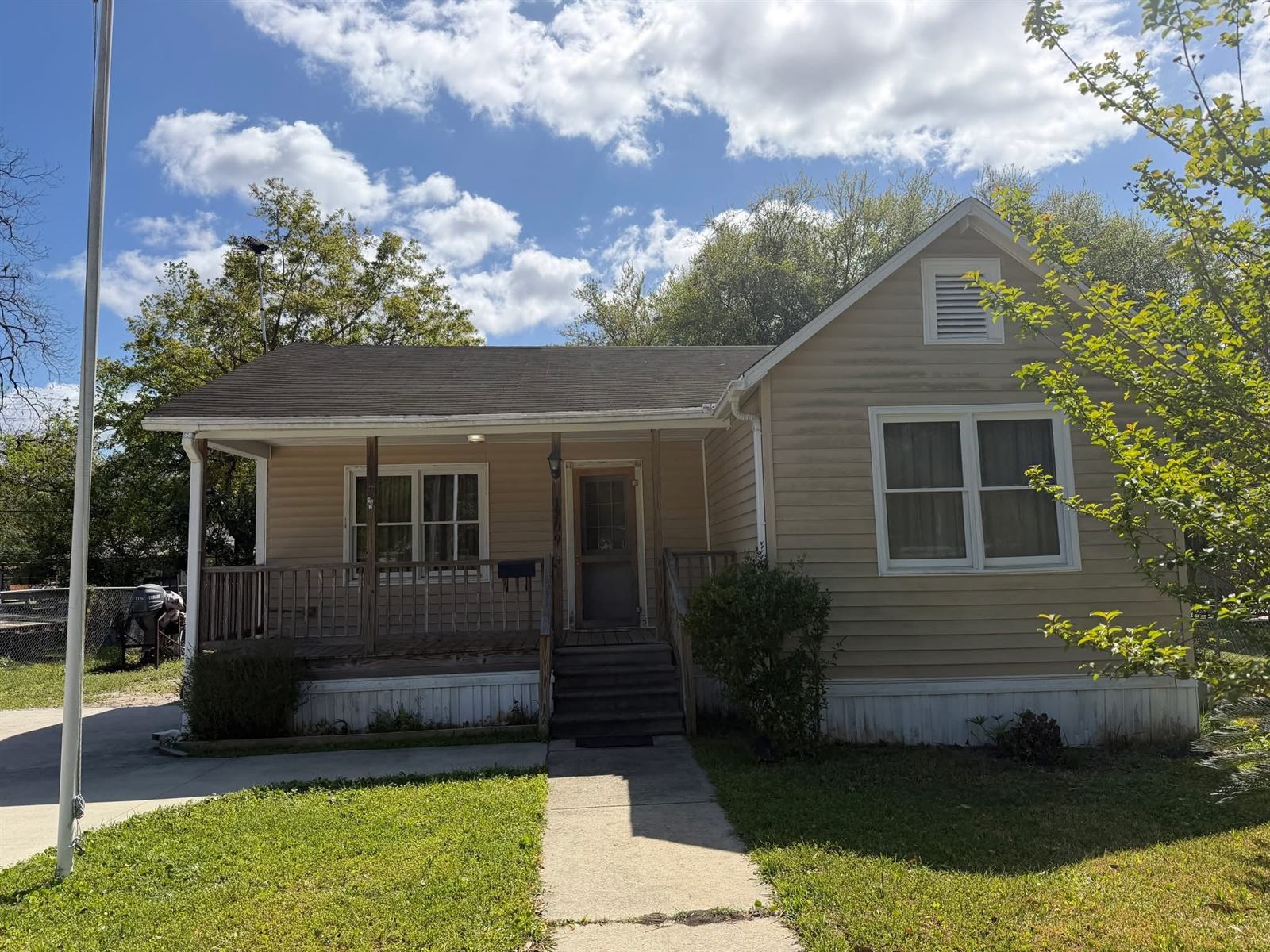 Dated bungalow exterior with worn siding, sagging porch rail and aging roof before renovation