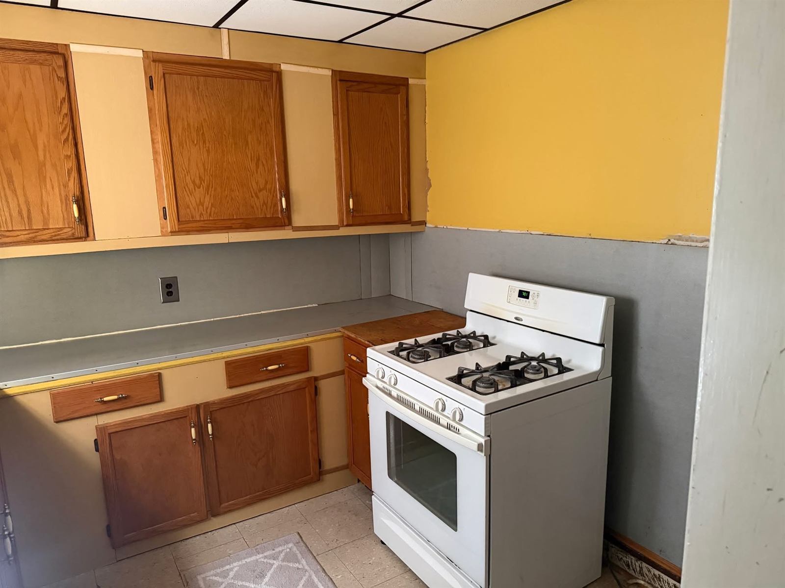 Original kitchen with dated oak cabinets, laminate counters and drop ceiling before renovation
